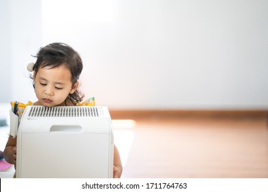 Cute Little Girl Standing Breathing At Air Purifier. Clean Air Concept.