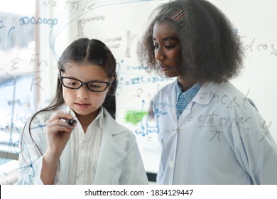 Cute Little Girl Student Child Learning Research And Doing A Chemical Experiment And Write Scientific Formulas And Calculations In Physics At Science Class.Education And Science Concept