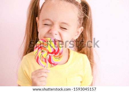 Cute little girl with sweet lollipop on color background