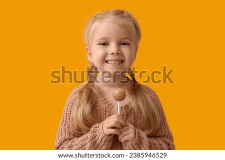 Cute little girl with sweet lollipop on yellow background