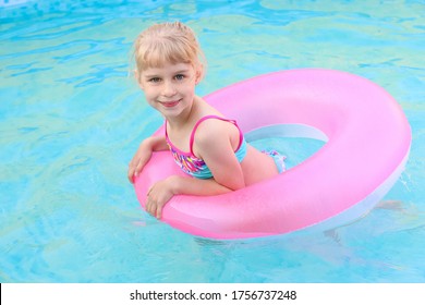 Cute little girl in swimming pool, swimming in inflatable ring. Summer lifestyle concept. Learning to swim on inflatable circle. Summer holidays, heat and water. Vacations