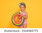 Cute little girl in swimsuit with inflatable ring eating ice cream on orange background