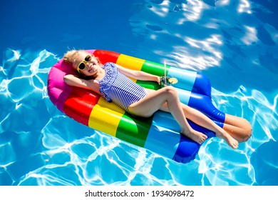 cute little girl in a swimsuit and sunglasses swims in a pool shaped like a large ice cream, top view, text space - Powered by Shutterstock