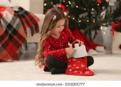 Cute little girl taking gift from Christmas stocking at home - Powered by Shutterstock