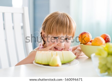 cute little girl taking water melon with fruits on the table