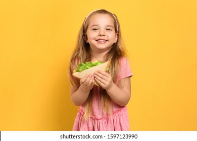 Cute little girl with tasty sandwich on yellow background - Powered by Shutterstock