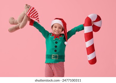 Cute little girl with teddy bear and Christmas cushion on pink background - Powered by Shutterstock