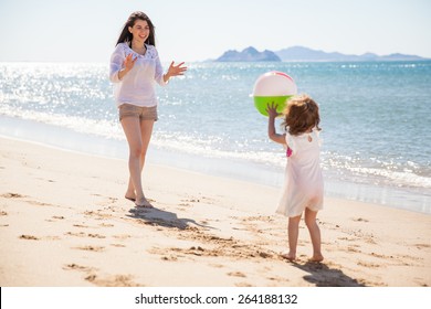 Cute little girl throwing a beach ball at her mom and having some fun on a sunny day