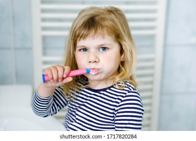 Das süße kleine Mädchen mit einer Zahnbürste in der Hand putzt sich die Zähne und lächelt. Funny glücklich gesund Kind lernt Morgenweg mit Waschen von Gesicht und Putzzähnen