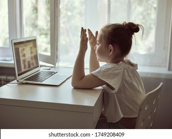 Cute little girl using laptop at home. Education, online study, home studying The girl at home communicates with friends on the Internet. Kids distance learning. High quality photo
