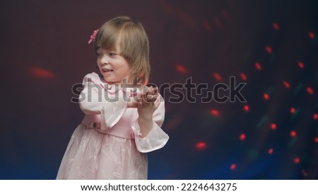 Cute little girl in vintage pink dress is spinning in dance and rejoicing. Concept of children theater productions and developing acting circles. Color music is shining and smoke is billowing