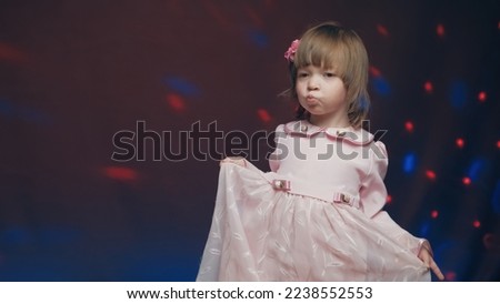 Cute little girl in vintage pink dress is spinning in dance and rejoicing. Concept of children theater productions and developing acting circles. Color music is shining and smoke is billowing