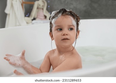 Cute little girl washing hair with shampoo in bathroom - Shutterstock ID 2311289653