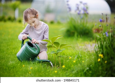 Cute Little Girl Watering Plants In The Garden