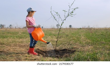 Cute little girl watering sapling tree from a watering can in Spring Day. Environment, save world and ecology concept - Shutterstock ID 2179330177