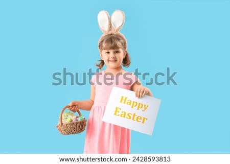 Cute little girl wearing bunny ears with Easter basket and gift card on blue background