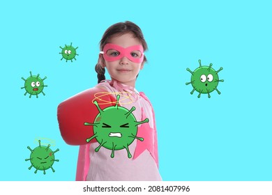 Cute little girl wearing superhero costume and boxing gloves fighting against viruses on turquoise background