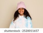 Cute little girl in winter clothes. Happy young girl kid image photography. Photo of smiling and laughing girl child on plain pastel brown background. Female kid winter outfit fashion concept.