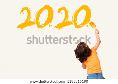 Cute little girl writing new year 2020 with painting brush on wall background
