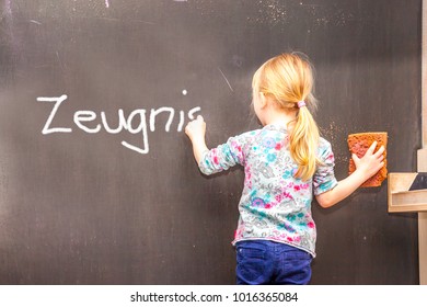Cute little girl writing Zeugnis on chalkboard in a classroom - Translation Testimony