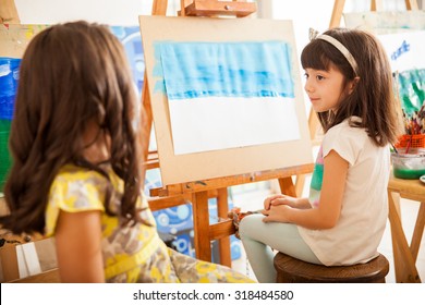 Cute Little Girls Comparing Each Other's Work And Sharing Ideas For Her Art Class At School