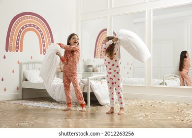 Cute Little Girls In Pajamas Having Pillow Fight On Bed At Home. Happy Childhood