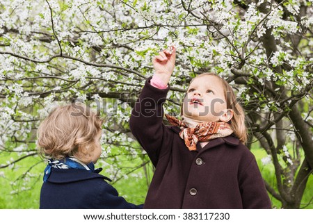 Cute little girls (sisters 3 and 4 years old) near flowering trees.