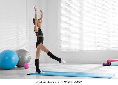 Cute Little Gymnast In Leotard On Mat Indoors