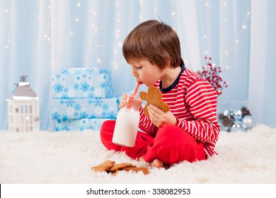 Cute Little Happy Boy, Eating Cookies And Drinking Milk, Waiting For Santa In Pajama On Christmas Eve Night