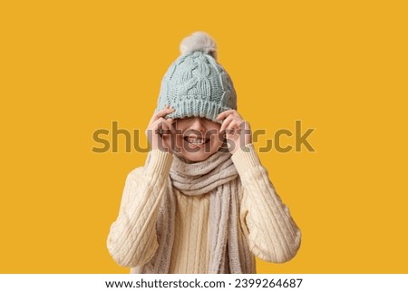 Cute little happy boy in winter clothes on yellow background