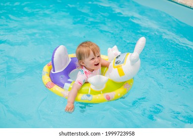 A Cute Little Happy Smiling Kid Baby Girl Is Swimming In The Swimming Pool Without Supervision Of Adults. Happy Childhood, Summer Leisure, Child Safety And Vacation Concept