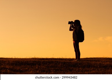 Cute little hiker girl looking with binoculars at sunset.Little hiker with binoculars