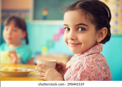 Cute little hispanic girl drinking milk at school