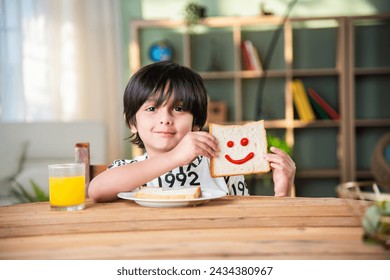Cute little Indian asian kids holding up a slice of bread with a cut out smiley face - Powered by Shutterstock