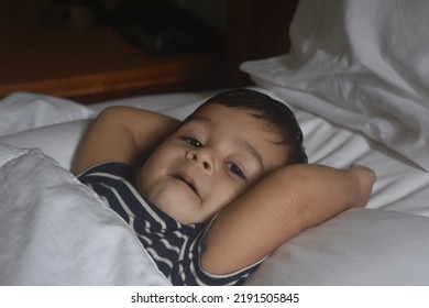 Cute Little Indian Boy Sleeping Over White Bed Sheet And Pillow.