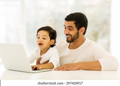 cute little indian boy using laptop with his father at home