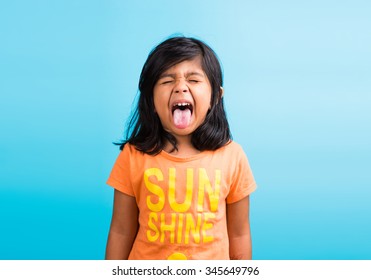 Cute little Indian girl with funny expressions posing for photoshoot, against sky blue background