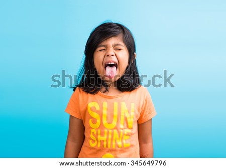 Cute little Indian girl with funny expressions posing for photoshoot, against sky blue background