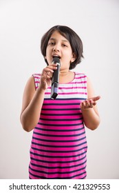 Cute Little Indian Girl Singing In Microphone, Standing Isolated Over White Background