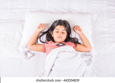 Cute Little Indian Girl Sleeping Over White Bed Sheet And Pillow. 