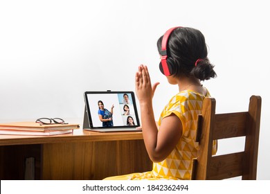 Cute Little Indian Girl Studying Online Using Her Laptop Or Tablet Computer At Home Or Attending School During Corona Pandemic Or Lockdown