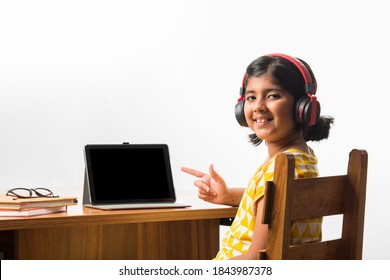 Cute Little Indian Girl Studying Online Using Her Laptop Or Tablet Computer At Home Or Attending School During Corona Pandemic Or Lockdown