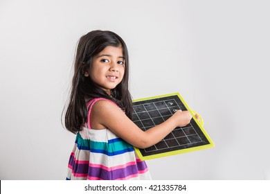 Cute little Indian girl writing abc on black school slate board, isolated over white background