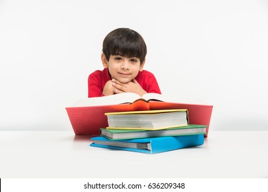 Cute Little Indian/Asian Boy Reading Book Over Study Table, Isolated Over White Background