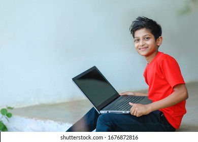 Cute Little Indian/Asian Boy Studying Or Playing Game With Laptop Computer