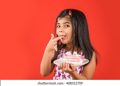 Cute Little Indian/Asian Girl Child Eating Piece Of Strawberry Or Chocolate Flavoured Pastry/cake In A Plate Or Licking Fingers. Isolated Over Colourful Background