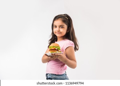 Cute Little Indian/Asian Girl Eating Burger On White Background
