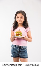 Cute Little Indian/Asian Girl Eating Burger On White Background
