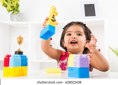 Cute little Indian/asian girl enjoying while playing with toys or blocks, sitting at table
