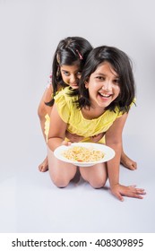 Cute Little Indian/Asian Girls Eating Yummy Chinese Noodles With Fork Or Chopsticks, Isolated Over Colourful Background